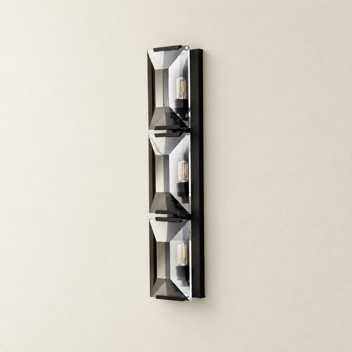 Triple crystal wall sconce with black mounting hardware and clear beveled panels.