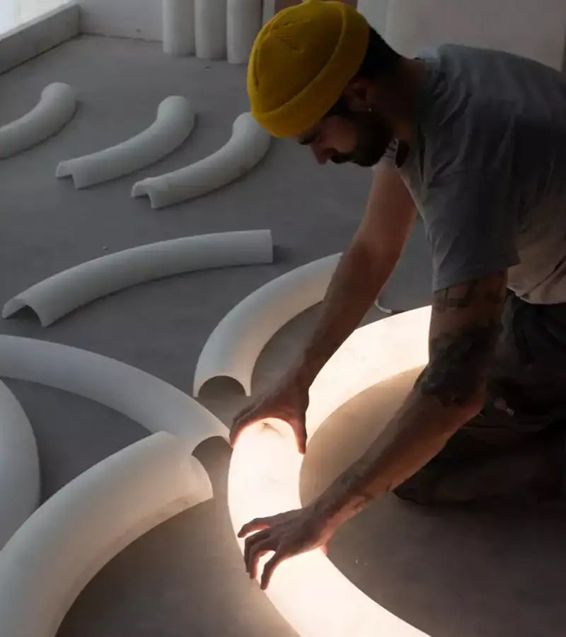 A glowing white curved pipe light fixture with a smooth, modern design.