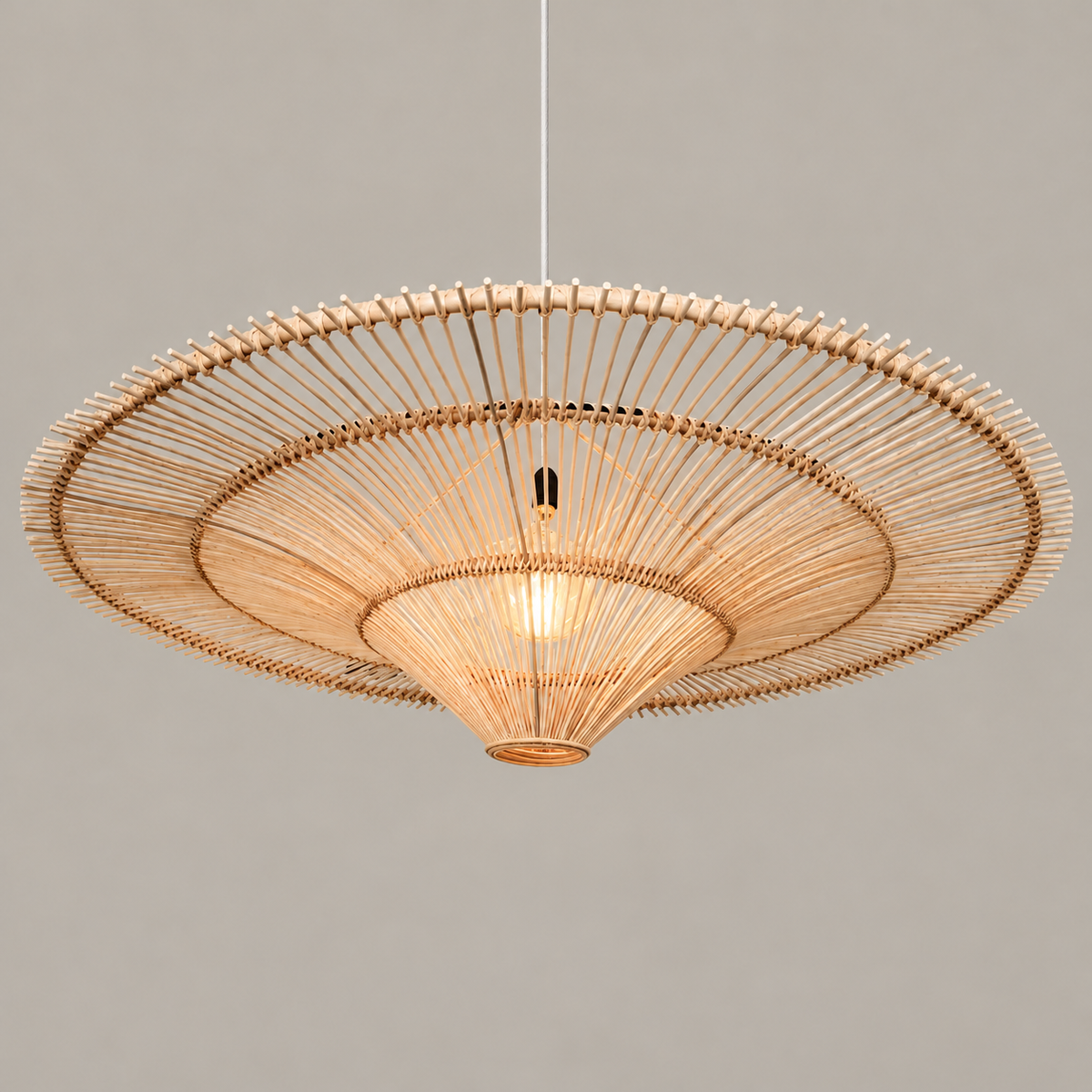 Beige CLWIC wicker pendant with its shallow curved shade, illuminated