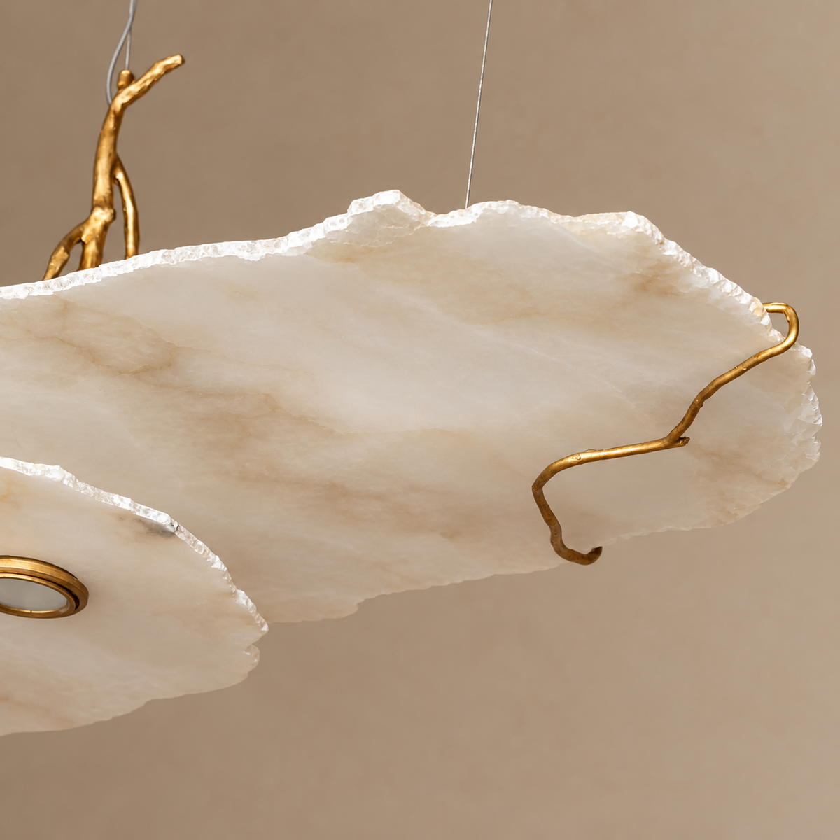 Close view of Y pendant’s honed alabaster slab, irregular stone edge and brass branch support